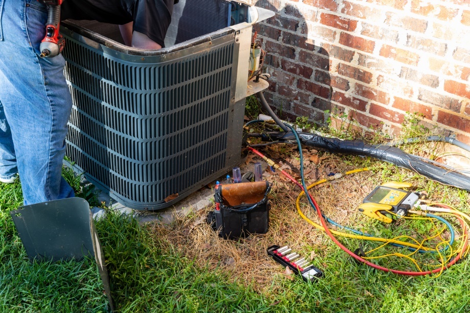 AC technician repairing an outdoor AC unit.