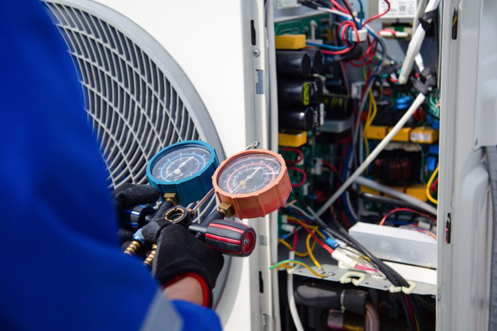Air conditioner technician is using a gauge to measure the refrigerant pressure of an air compressor