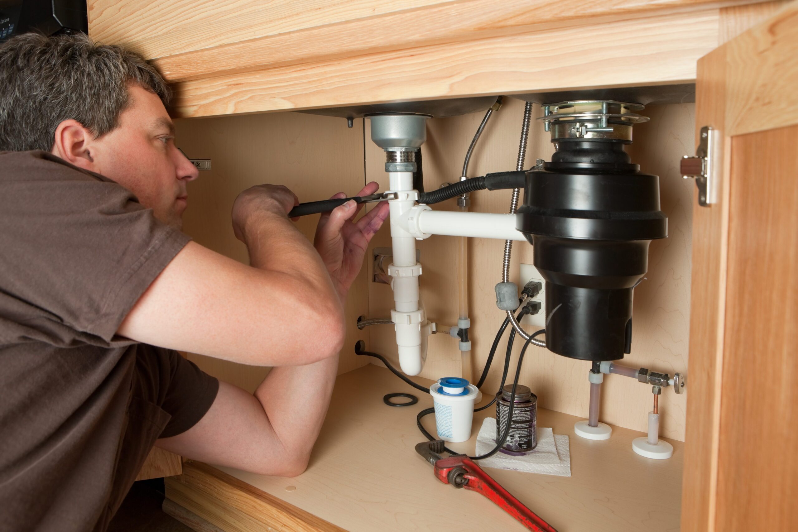 Plumber fixing an under-sink garbage disposal