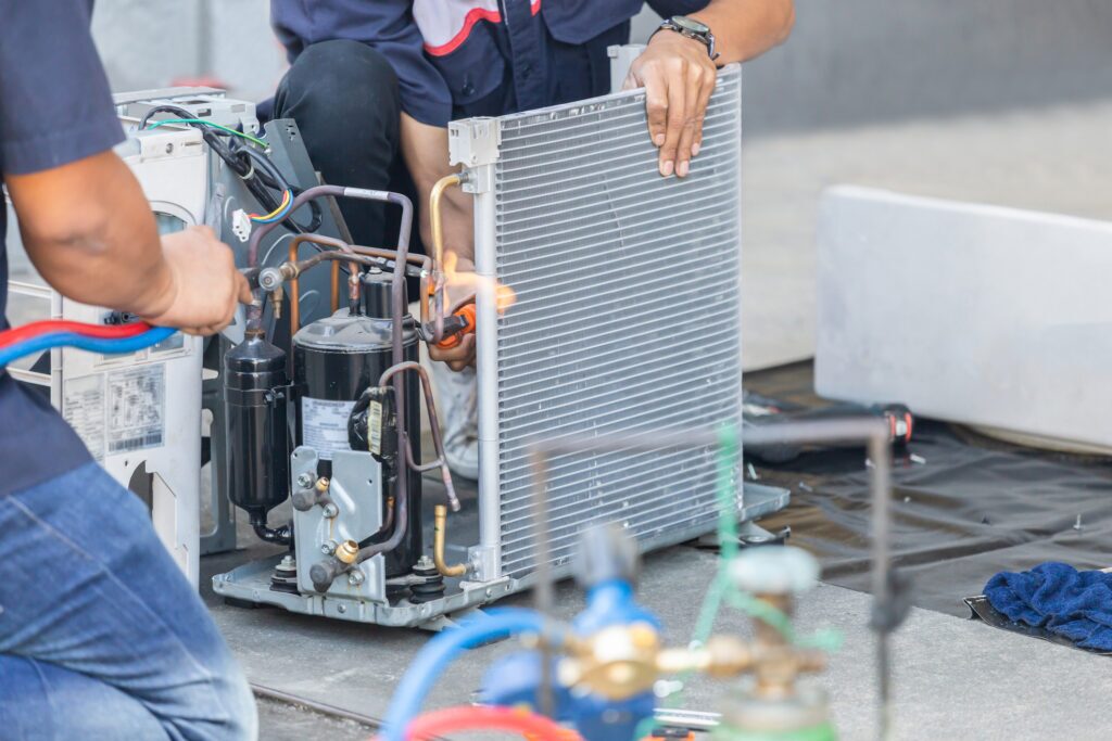 Close up of an AC repair team using fuel gases and oxygen to weld or cut metals