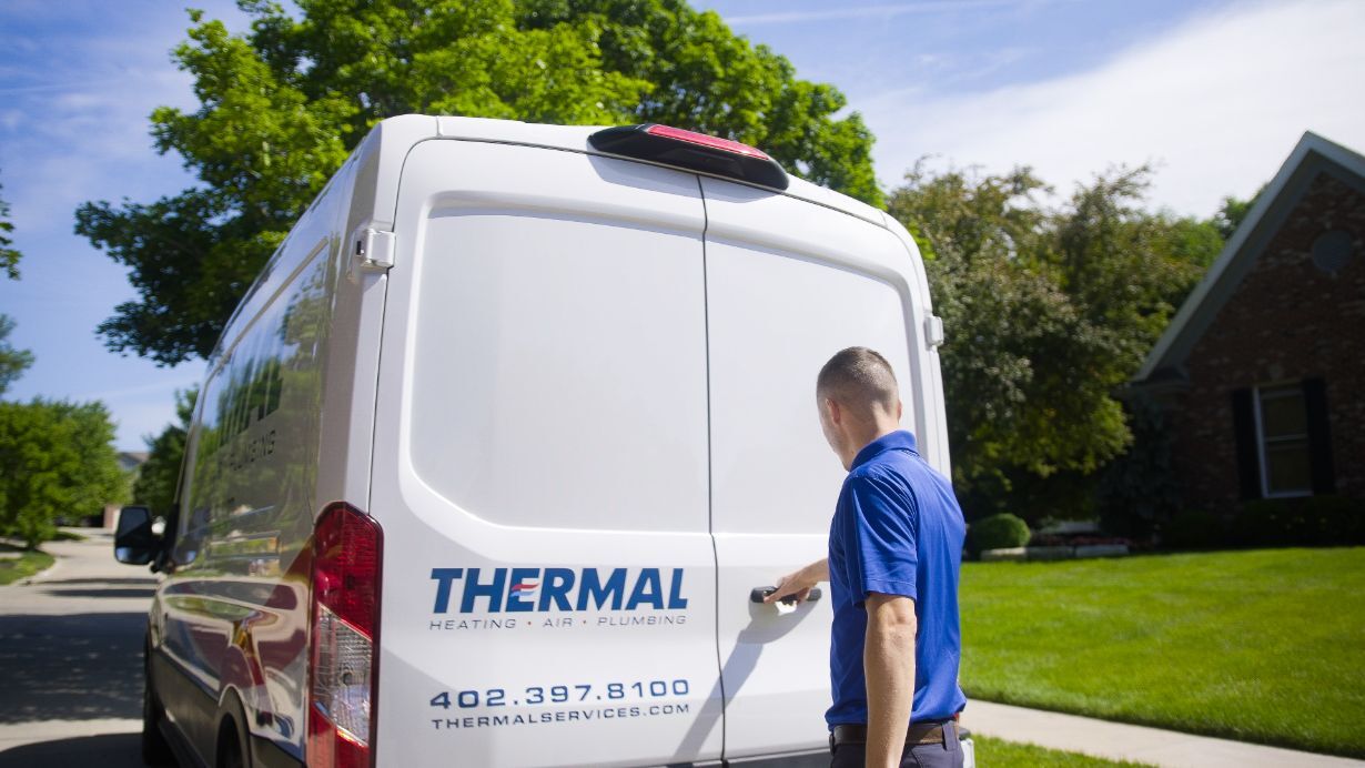 Professional HVAC technician in red uniform performing a tune-up modern heat pump unit